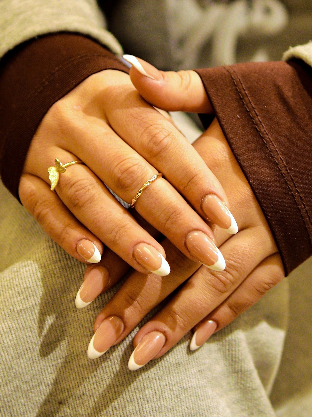 As mãos de uma mulher com uma manicure francesa ousada numa combinação de bege e branco em unhas compridas amendoadas