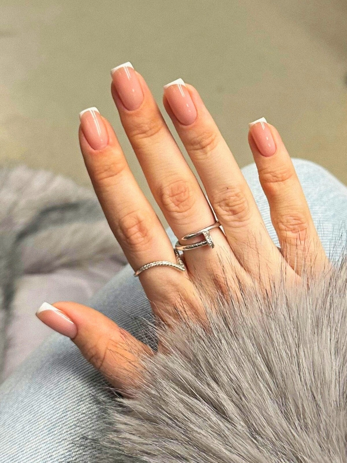 A mão de uma mulher com uma manicure francesa de microlinhas em unhas quadradas