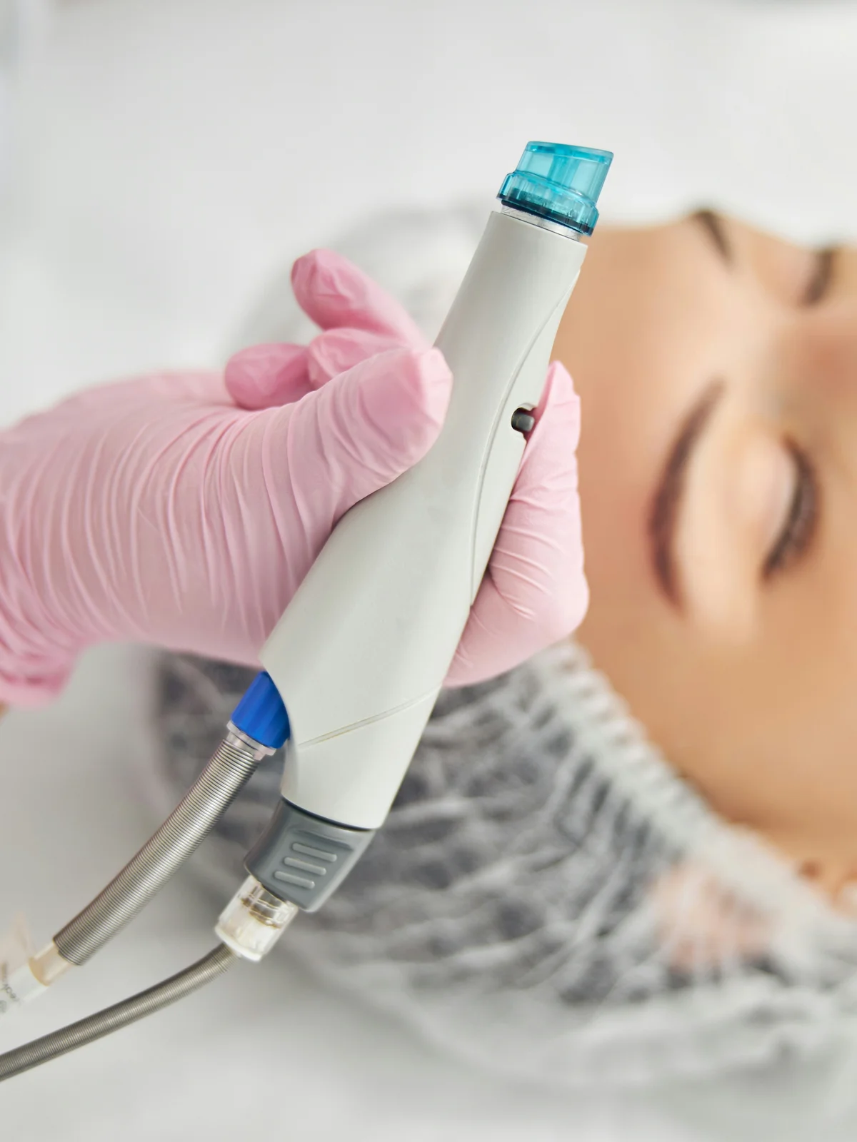 Grande plano de um aparelho HydraFacial com ponta em espiral segurado por uma especialista